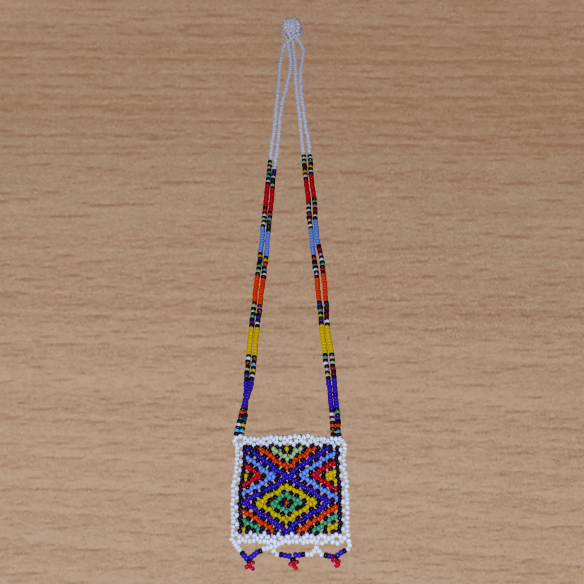 Collier sud-africain traditionnel "Zulu Love Letter" avec pendentif décoré de motifs ethniques zoulous composé d'un tissage de perles de rocaille blanches et multicolores.