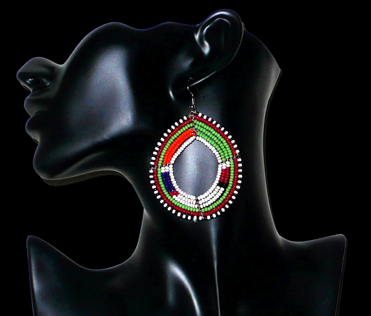 Longues boucles d'oreilles africaines Massai faites de perles de rocaille vertes, blanches, orange, rouges, bleu foncé et noires fixées sur six rangées de fils de fer montés en cercles. Elles mesurent 8 cm de long et 5,5 cm de larges et se portent avec des crochets en acier inoxydable sur des oreilles percées. Timeless Fineries