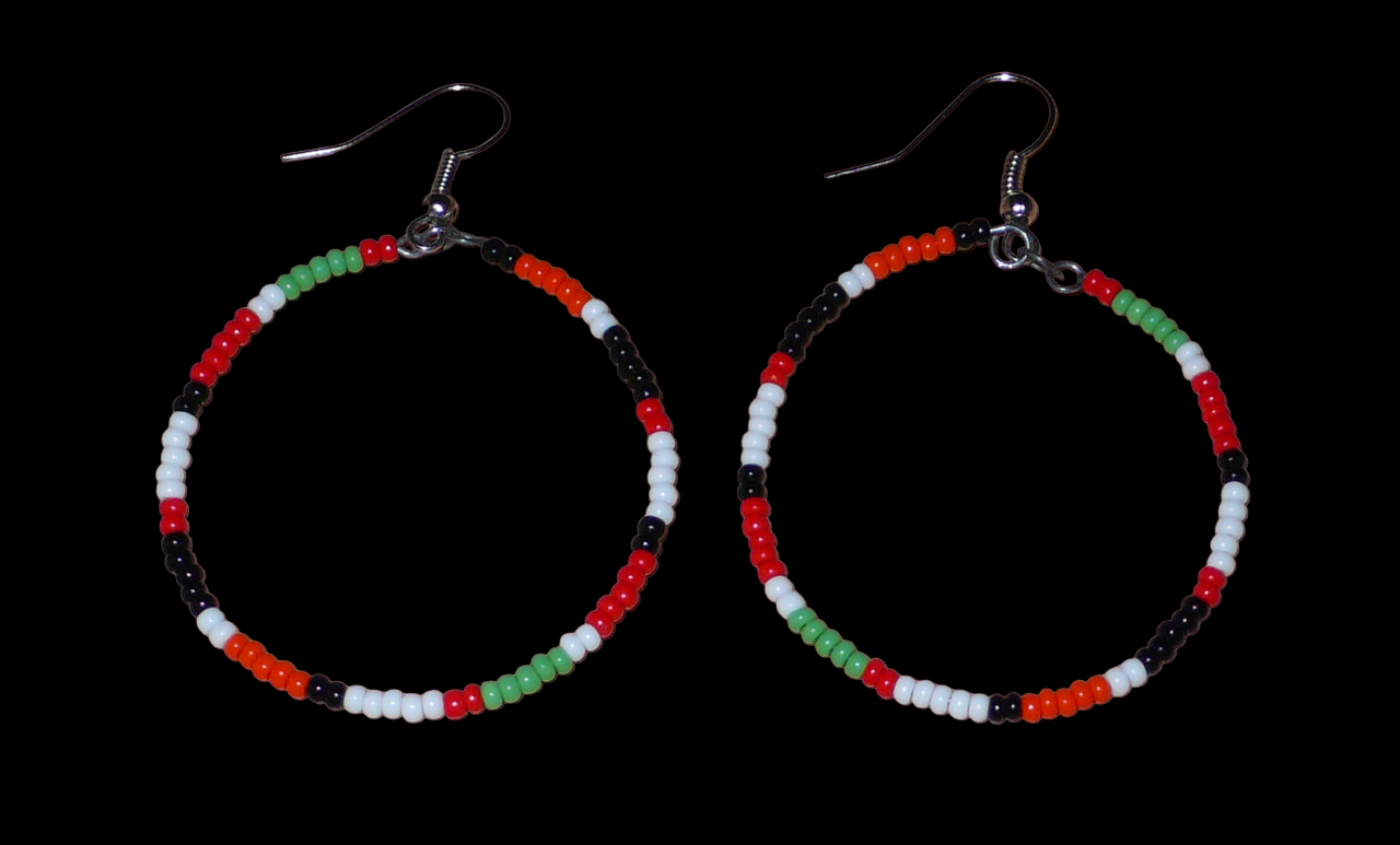 Créoles aux couleurs ethniques Massai faites de perles de rocaille rouges, vertes, noires, blanches et orange glissées sur un brin de fils de fer monté en cercle. Elles mesurent 6 cm de long et 4 cm de large, et se portent avec des crochets en acier inoxydable sur des oreilles percées.