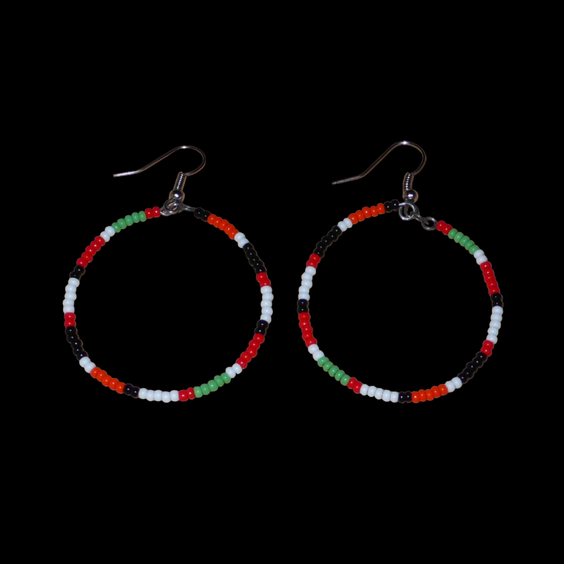Créoles aux couleurs ethniques Massai faites de perles de rocaille rouges, vertes, noires, blanches et orange glissées sur un brin de fils de fer monté en cercle. Elles mesurent 6 cm de long et 4 cm de large, et se portent avec des crochets en acier inoxydable sur des oreilles percées.