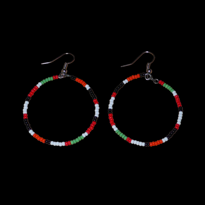 Créoles aux couleurs ethniques Massai faites de perles de rocaille rouges, vertes, noires, blanches et orange glissées sur un brin de fils de fer monté en cercle. Elles mesurent 6 cm de long et 4 cm de large, et se portent avec des crochets en acier inoxydable sur des oreilles percées.