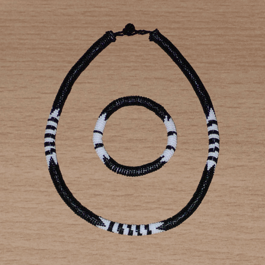 Parure de bijoux sud-africains traditionnels à motifs zoulous comprenant un collier et un bracelet composés de perles de rocaille noires et blanches.