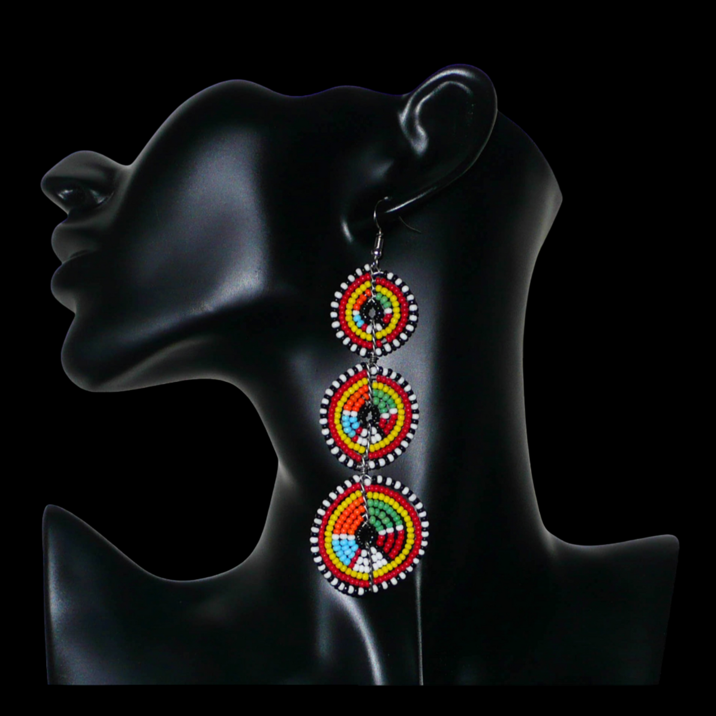 Longues boucles d'oreilles africaines de tradition Massai aux design et couleurs évoquant le style ethnique afro chic des années 70. Elles se composent de perles de rocaille multicolores glissées sur des fils de fer montés en forme de trois cercles superposés. Ces boucles d'oreilles mesurent 10.5 cm de long et 3 cm de large ; elles se portent avec des crochets en acier inoxydable sur des oreilles percées.