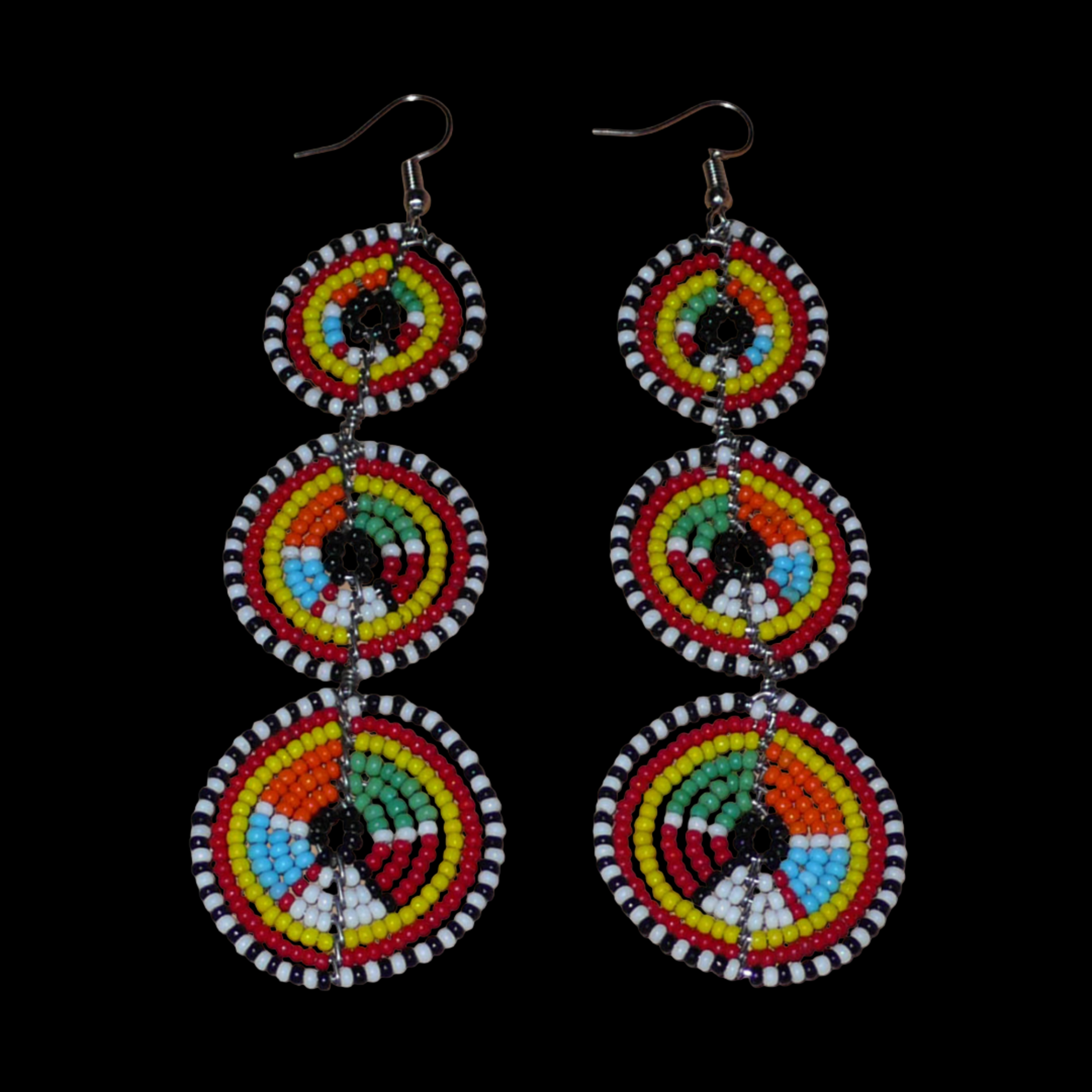 Longues boucles d'oreilles africaines de tradition Massai aux design et couleurs évoquant le style ethnique afro chic des années 70. Elles se composent de perles de rocaille multicolores glissées sur des fils de fer montés en forme de trois cercles superposés. Ces boucles d'oreilles mesurent 10.5 cm de long et 3 cm de large ; elles se portent avec des crochets en acier inoxydable sur des oreilles percées.