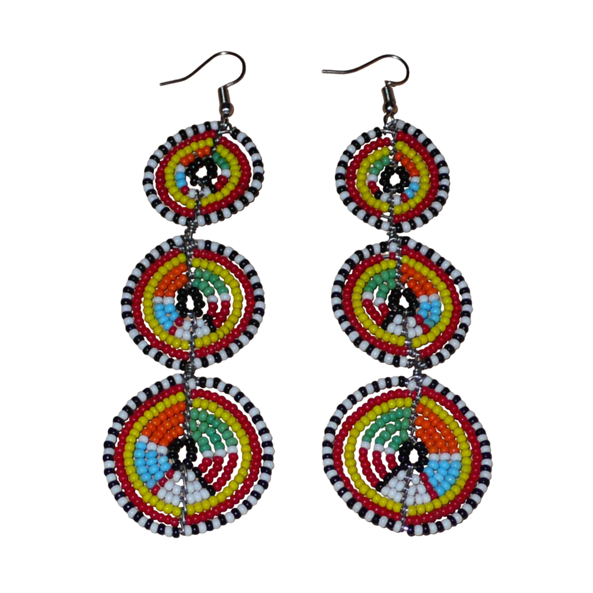 Longues boucles d'oreilles africaines de tradition Massai aux design et couleurs évoquant le style ethnique afro chic des années 70. Elles se composent de perles de rocaille multicolores glissées sur des fils de fer montés en forme de trois cercles superposés. Ces boucles d'oreilles mesurent 10.5 cm de long et 3 cm de large ; elles se portent avec des crochets en acier inoxydable sur des oreilles percées.