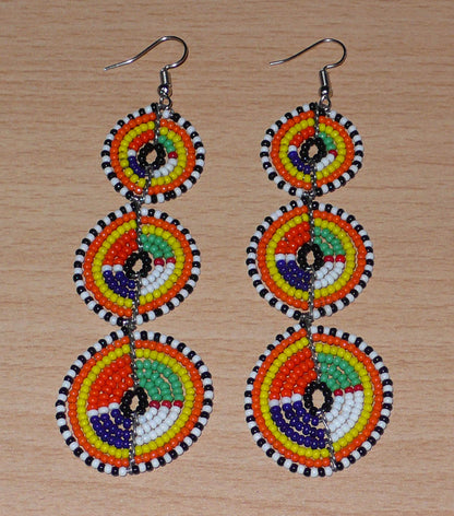 Longues boucles d'oreilles ethniques afro chic composées de perles de rocaille multicolores montées en trois cercles superposés. Elles mesurent 10,5 cm de long et 3 cm de large. 