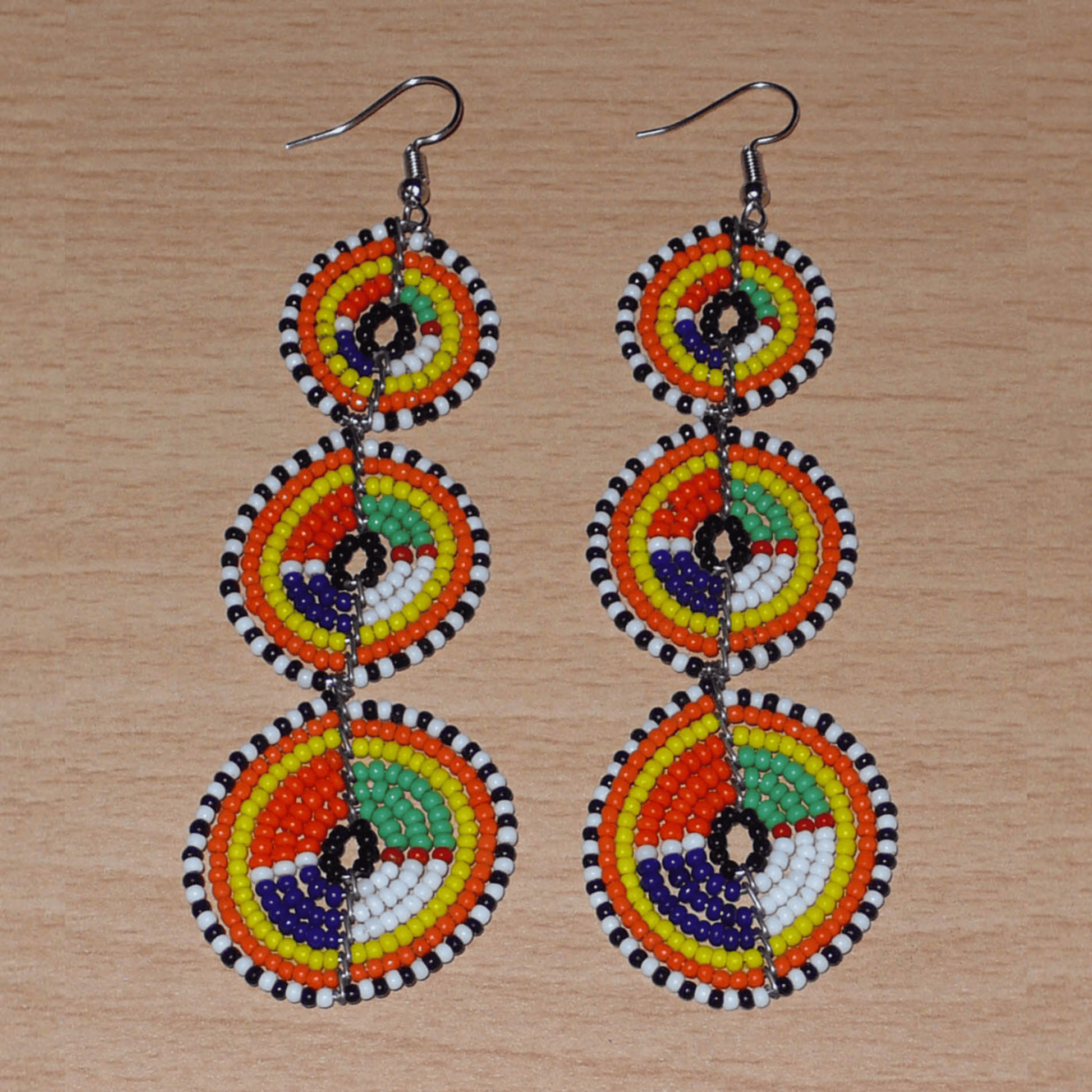 Longues boucles d'oreilles ethniques afro chic composées de perles de rocaille multicolores montées en trois cercles superposés. Elles mesurent 10,5 cm de long et 3 cm de large. 