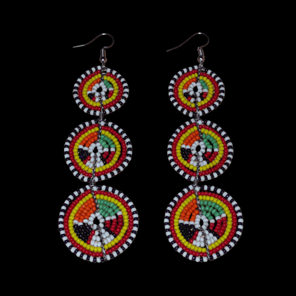 Longues boucles d'oreilles africaines composées de trois cercles superposés en perles de rocaille multicolores. Elles mesurent 11 cm de long et 3 cm de large et se portent avec des crochets en acier inoxydable sur des oreilles percées.