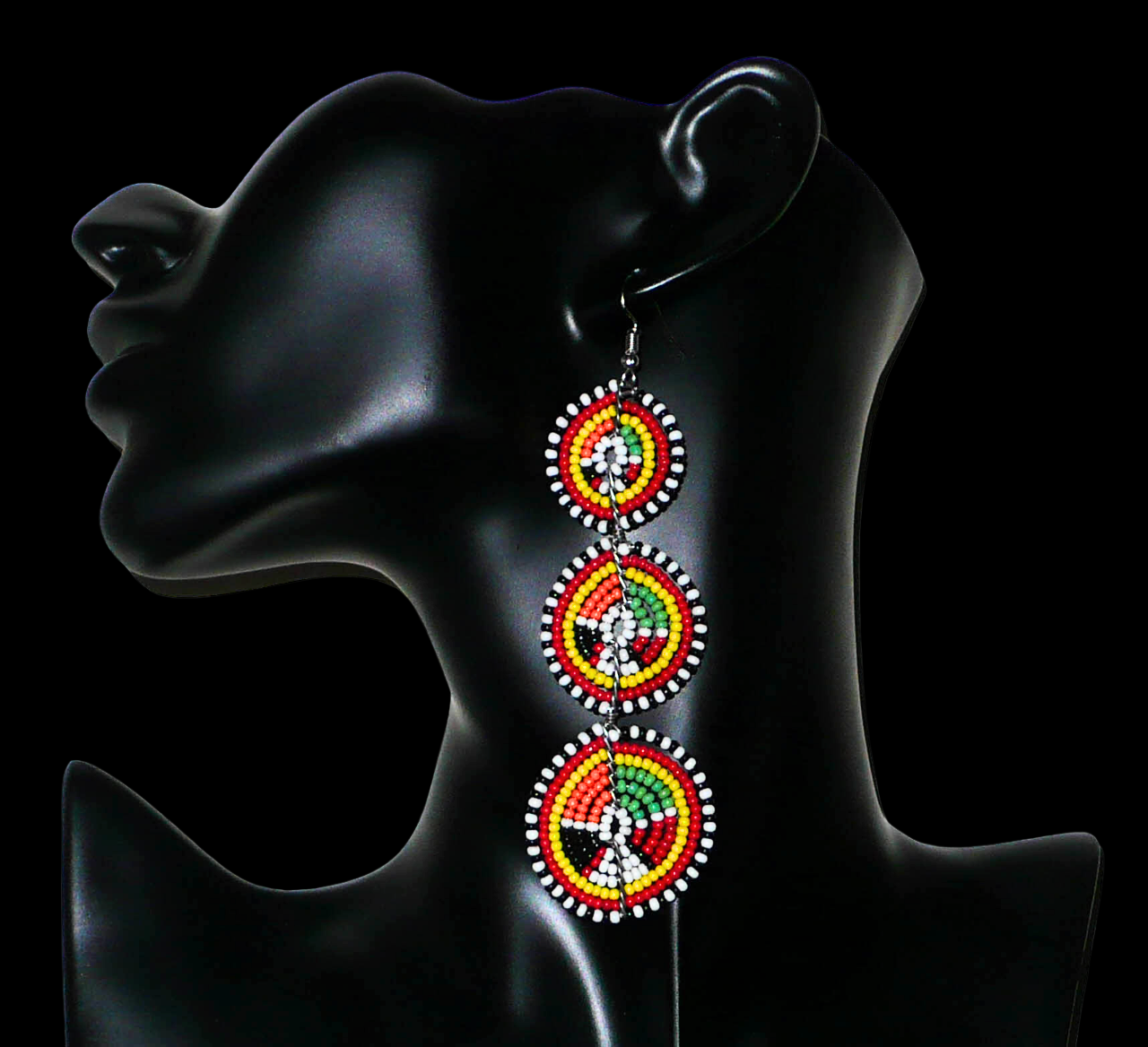 Longues boucles d'oreilles africaines composées de trois cercles superposés en perles de rocaille multicolores. Elles mesurent 11 cm de long et 3 cm de large et se portent avec des crochets en acier inoxydable sur des oreilles percées.