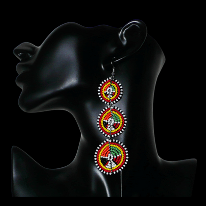 Longues boucles d'oreilles africaines composées de trois cercles superposés en perles de rocaille multicolores. Elles mesurent 11 cm de long et 3 cm de large et se portent avec des crochets en acier inoxydable sur des oreilles percées.