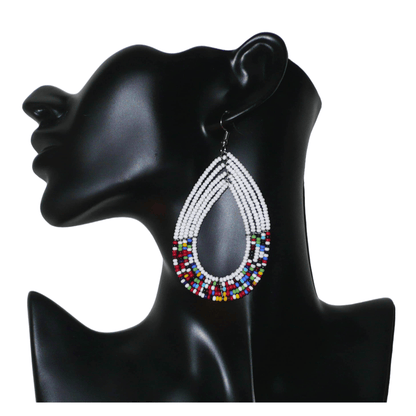 Longues boucles d'oreilles ethniques multi-rangs faites de perles de rocaille blanches et multicolores montées en forme de gouttes. Elles mesurent 9 cm de long et 4.5 cm de large, et se portent sur des oreilles percées.