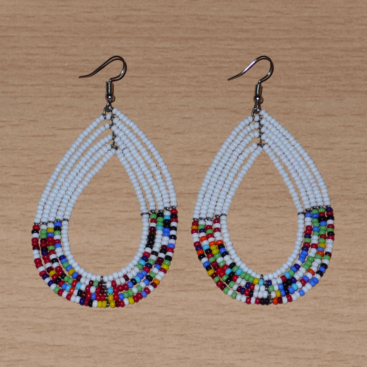 Longues boucles d'oreilles ethniques multi-rangs faites de perles de rocaille blanches et multicolores montées en forme de gouttes. Elles mesurent 9 cm de long et 4.5 cm de large, et se portent sur des oreilles percées.