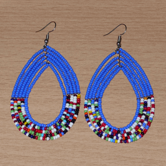 Longues boucles d'oreilles kenyanes au style afro bohème composées de perles de rocaille bleues et multicolores montées en forme de gouttes. Elles mesurent 9 cm de long et 4.5 cm de large, et se portent sur des oreilles percées.