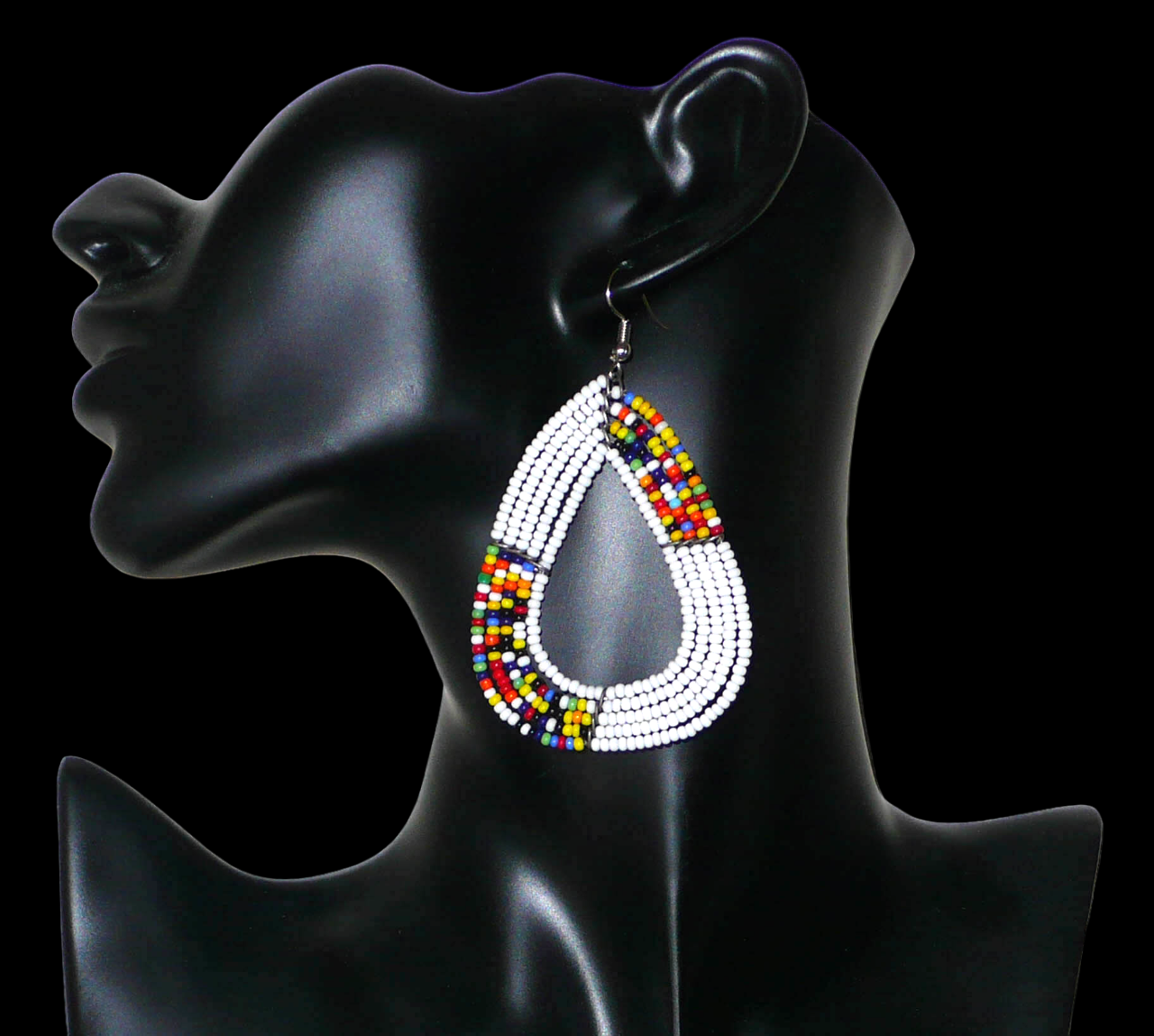 Longues et larges boucles d'oreilles kenyanes composées de perles de rocaille blanches et multicolores glissées sur cinq rangées de fils de fer montés en forme de gouttes légèrement triangulaires. Elles mesurent 8 cm de long et 5 cm de large et se portent avec des crochets en acier inoxydable sur des oreilles percées.