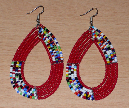 Longues boucles d'oreilles Massai multi-rangs rouges et multicolores en perles de rocaille. Elles mesurent 9 cm de long et 4.5 cm de large et se portent sur des oreilles percées.
