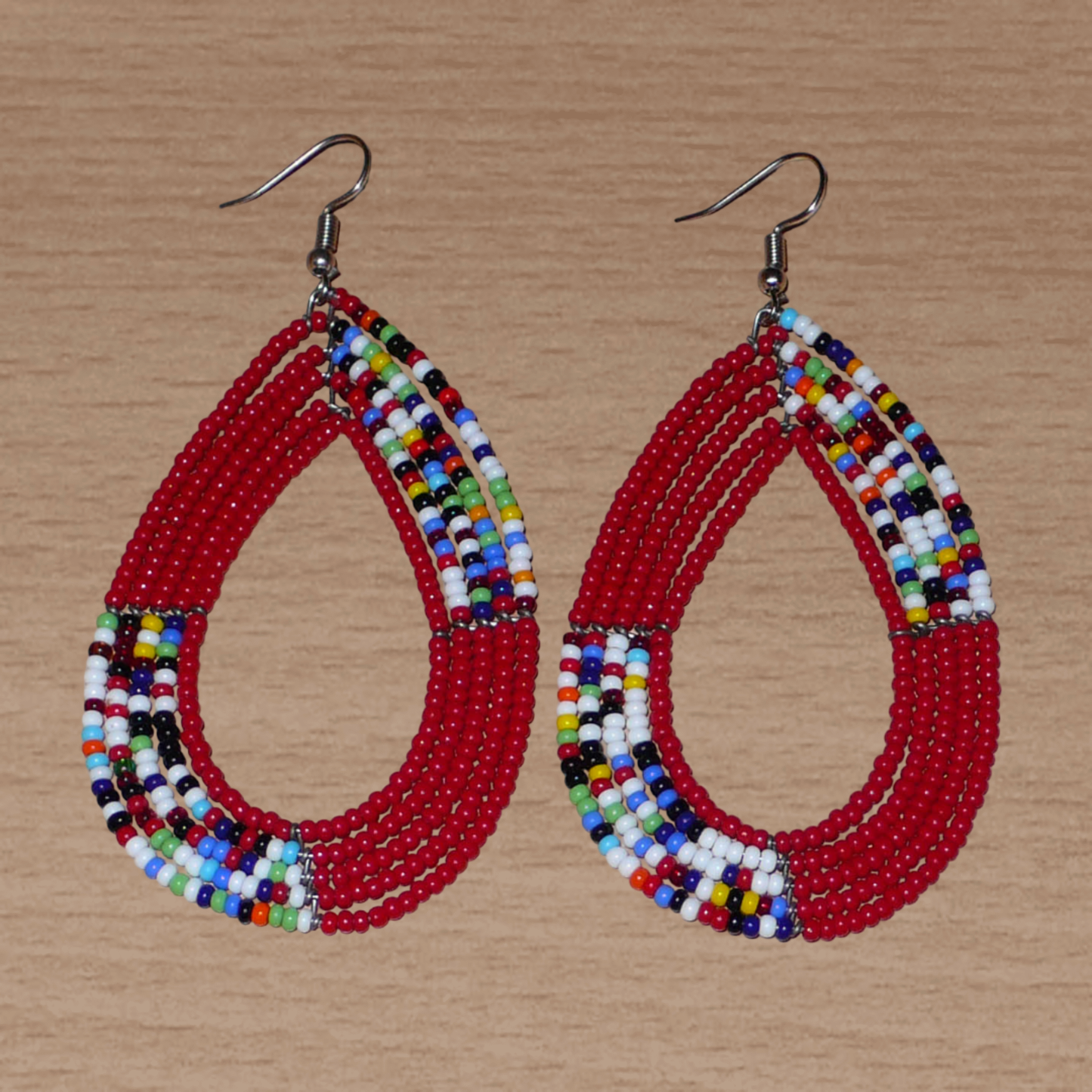 Longues boucles d'oreilles Massai multi-rangs rouges et multicolores en perles de rocaille. Elles mesurent 9 cm de long et 4.5 cm de large et se portent sur des oreilles percées.