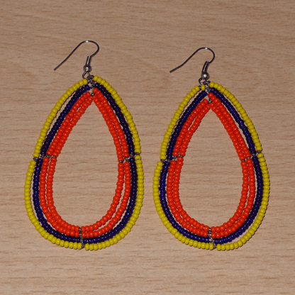 Longues boucles d'oreilles tricolores composées de perles de rocaille orange, jaunes et bleu marine enfilées sur quatre rangées de fils de fer montés en forme de gouttes. Ces boucles d'oreilles "oversized" mesurent 8.5 cm de long et 4.5 cm de large ; elles se portent avec des crochets en acier inoxydable sur des oreilles percées.