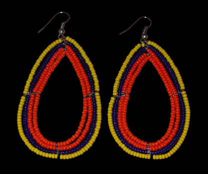 Longues boucles d'oreilles tricolores composées de perles de rocaille orange, jaunes et bleu marine enfilées sur quatre rangées de fils de fer montés en forme de gouttes. Ces boucles d'oreilles "oversized" mesurent 8.5 cm de long et 4.5 cm de large ; elles se portent avec des crochets en acier inoxydable sur des oreilles percées.