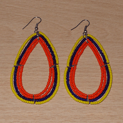 Longues et larges boucles d'oreilles ethniques multi-rangs en perles de rocaille orange, jaunes et bleu marine. Elles mesurent 8.5 cm de long et 4.5 cm de large, et se portent sur des oreilles percées.