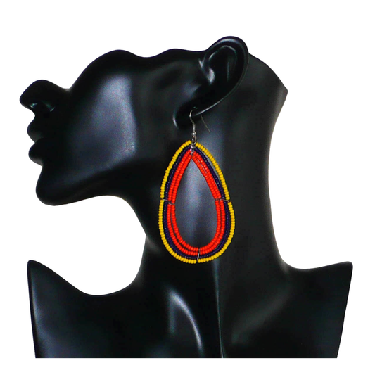 Longues et larges boucles d'oreilles ethniques multi-rangs en perles de rocaille orange, jaunes et bleu marine. Elles mesurent 8.5 cm de long et 4.5 cm de large, et se portent sur des oreilles percées.