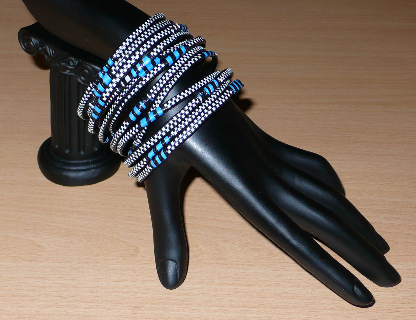 Lot de douze bracelets africains tricolores en plastique recyclé bleu, noir et blanc.