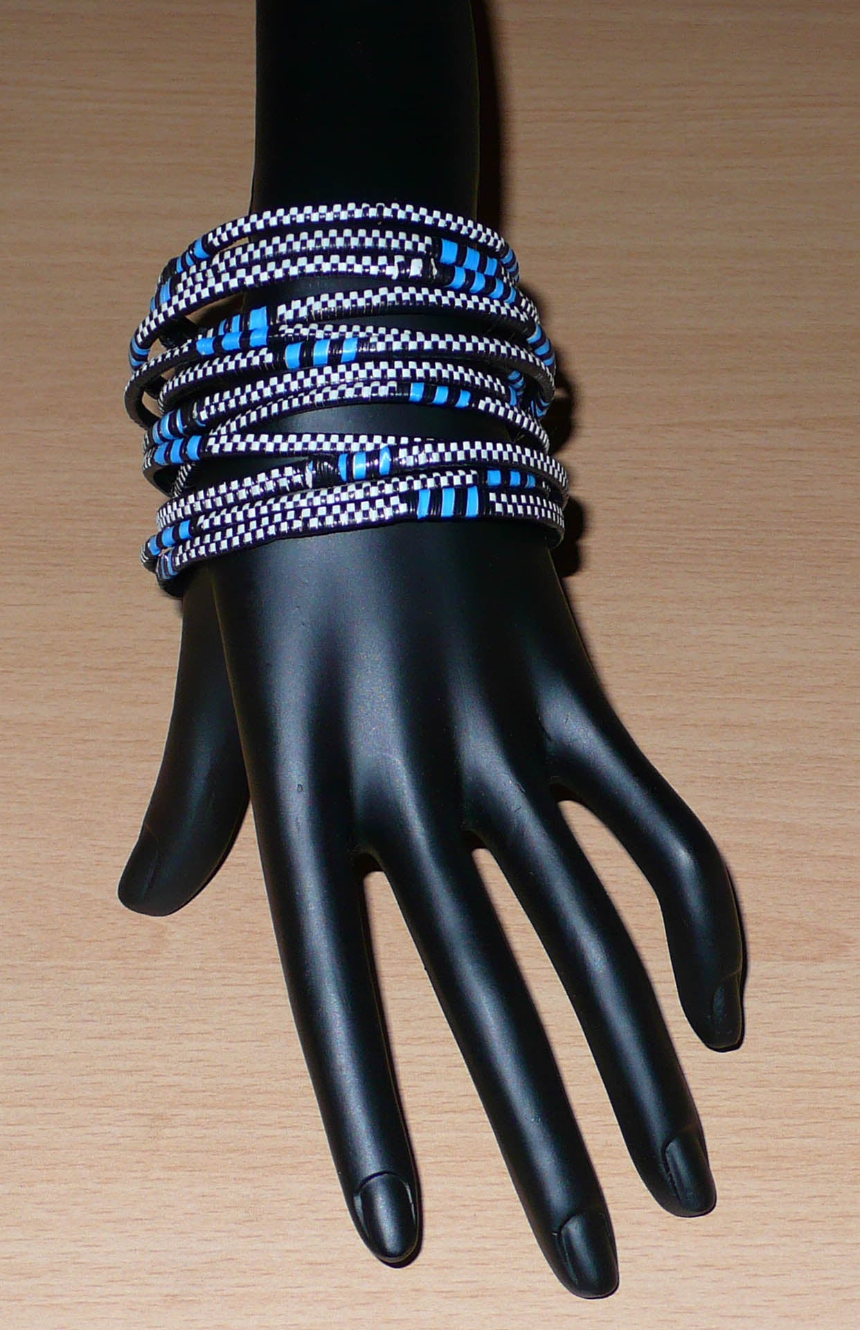 Lot de douze bracelets africains tricolores en plastique recyclé bleu, noir et blanc.