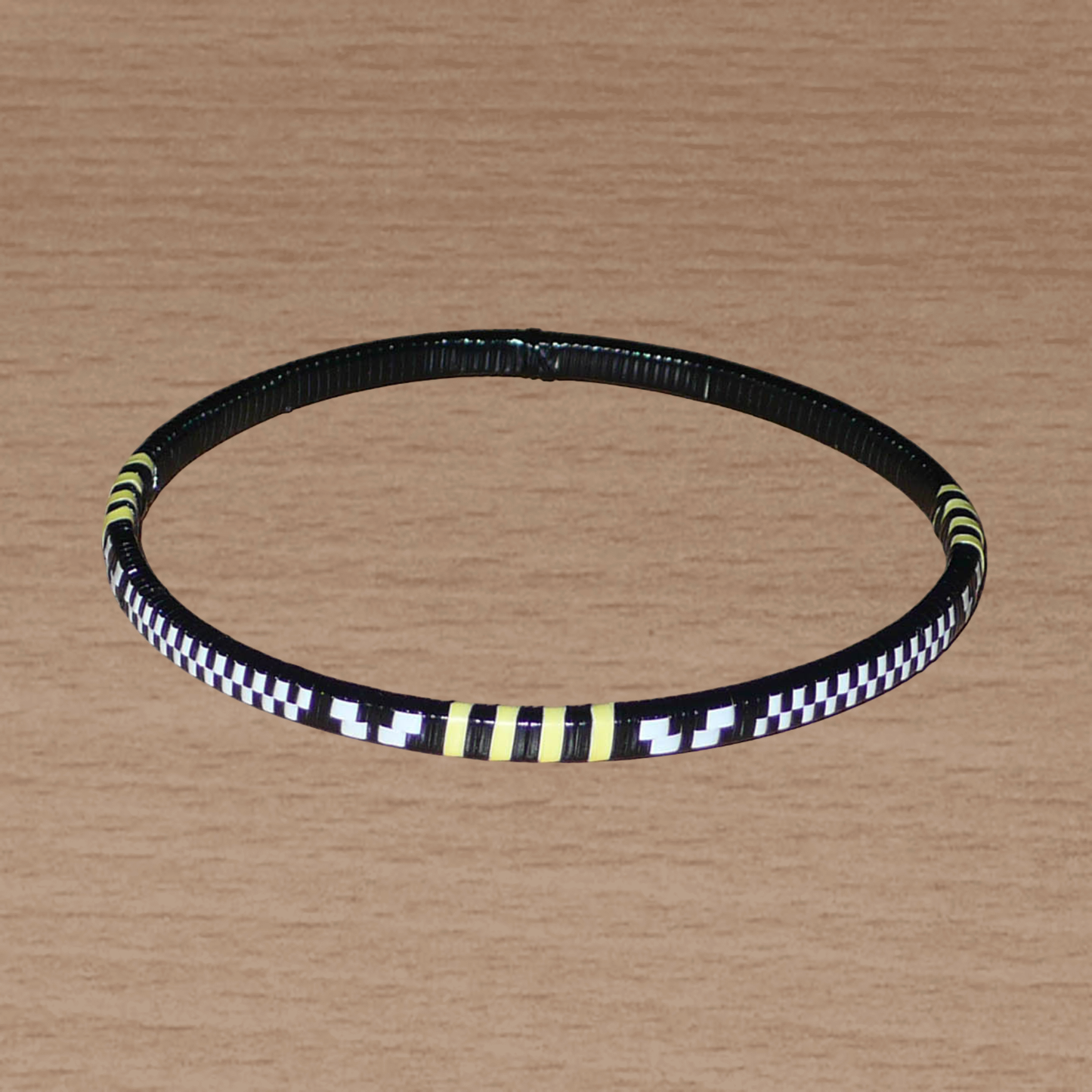 Lot de douze bracelets africains tricolores fins et légers à porter, composés de fines bandes de plastique recyclé jaune, noir et blanc.