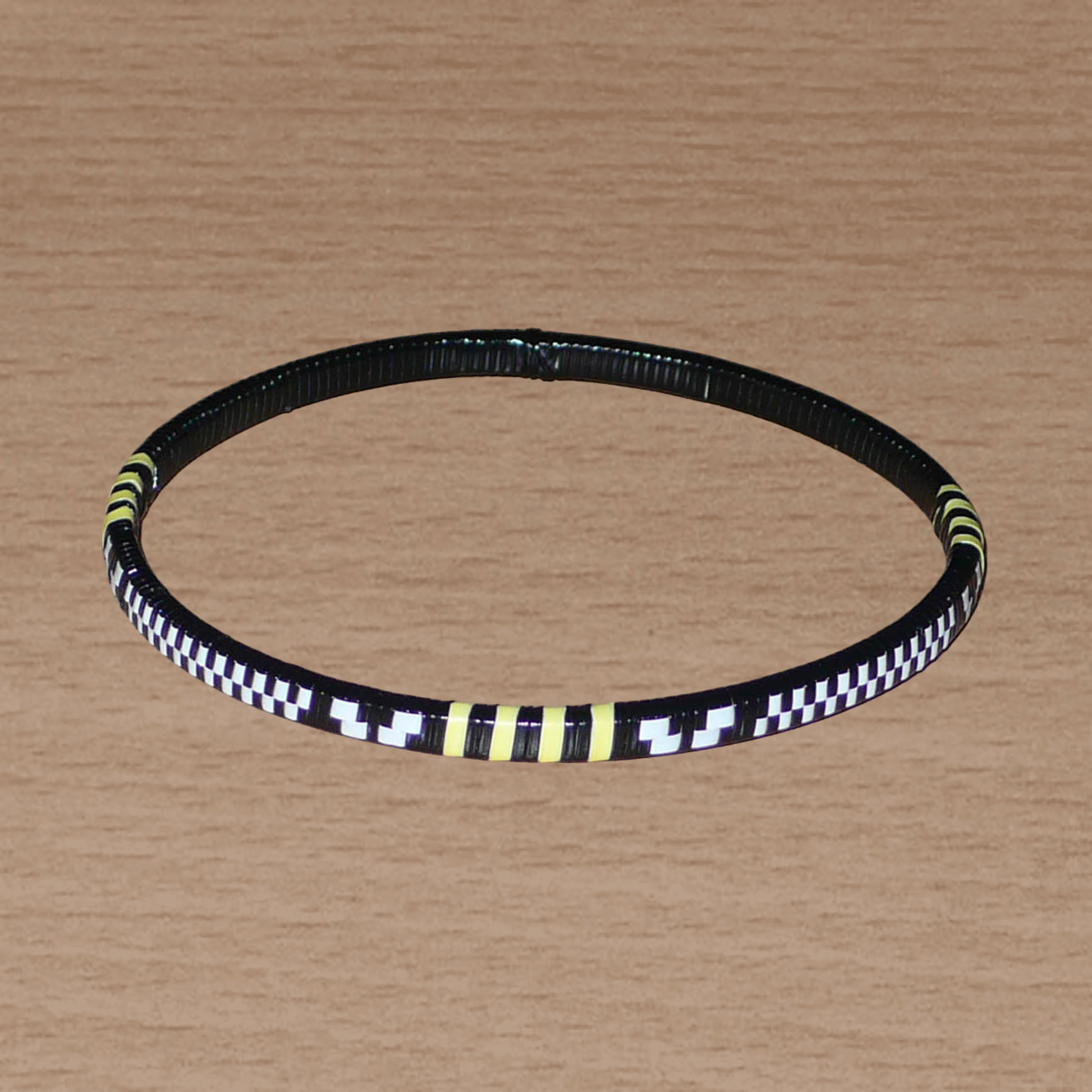 Lot de douze bracelets africains tricolores fins et légers à porter, composés de fines bandes de plastique recyclé jaune, noir et blanc.