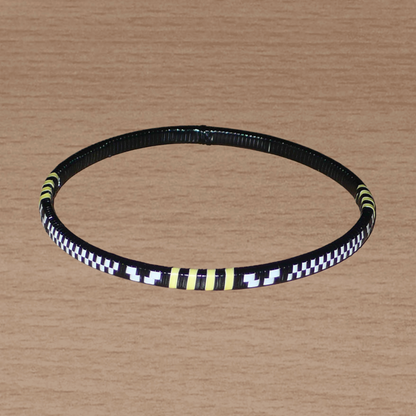 Lot de douze bracelets africains tricolores fins et légers à porter, composés de fines bandes de plastique recyclé jaune, noir et blanc.