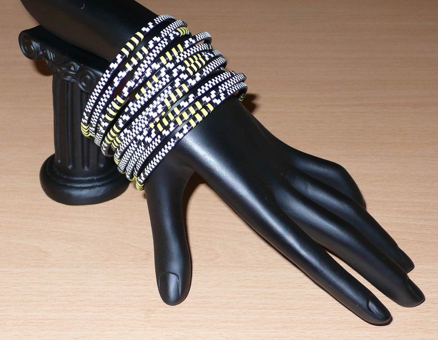 Lot de douze bracelets africains tricolores fins et légers à porter, composés de fines bandes de plastique recyclé jaune, noir et blanc.