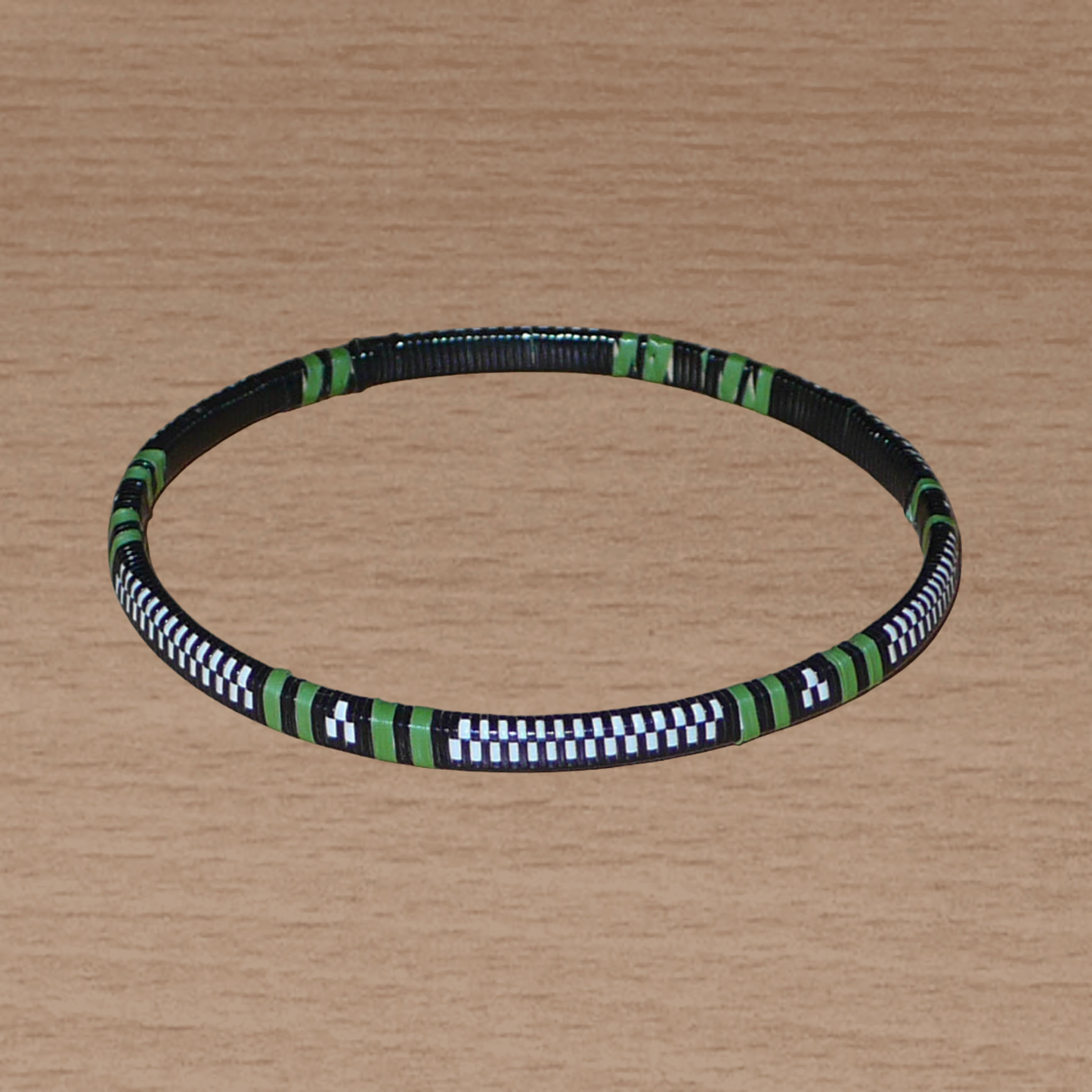 Lot de douze bracelets africains tricolores, fabriqués au Burkina Faso dans une optique eco-responsable, composés de fines bandes de plastique recyclé vert khaki, blanc et noir.