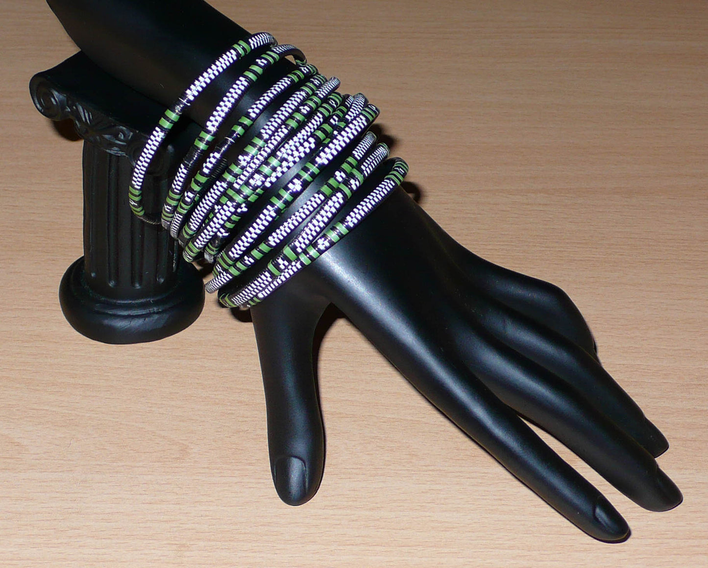 Lot de douze bracelets africains tricolores, fabriqués au Burkina Faso dans une optique eco-responsable, composés de fines bandes de plastique recyclé vert khaki, blanc et noir.