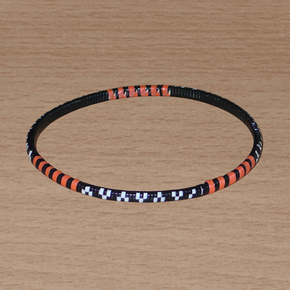 Lot de douze bracelets africains tricolores, fabriqués au Burkina Faso dans une démarche eco-responsable, composés de plastique recyclé orange, noir et blanc.