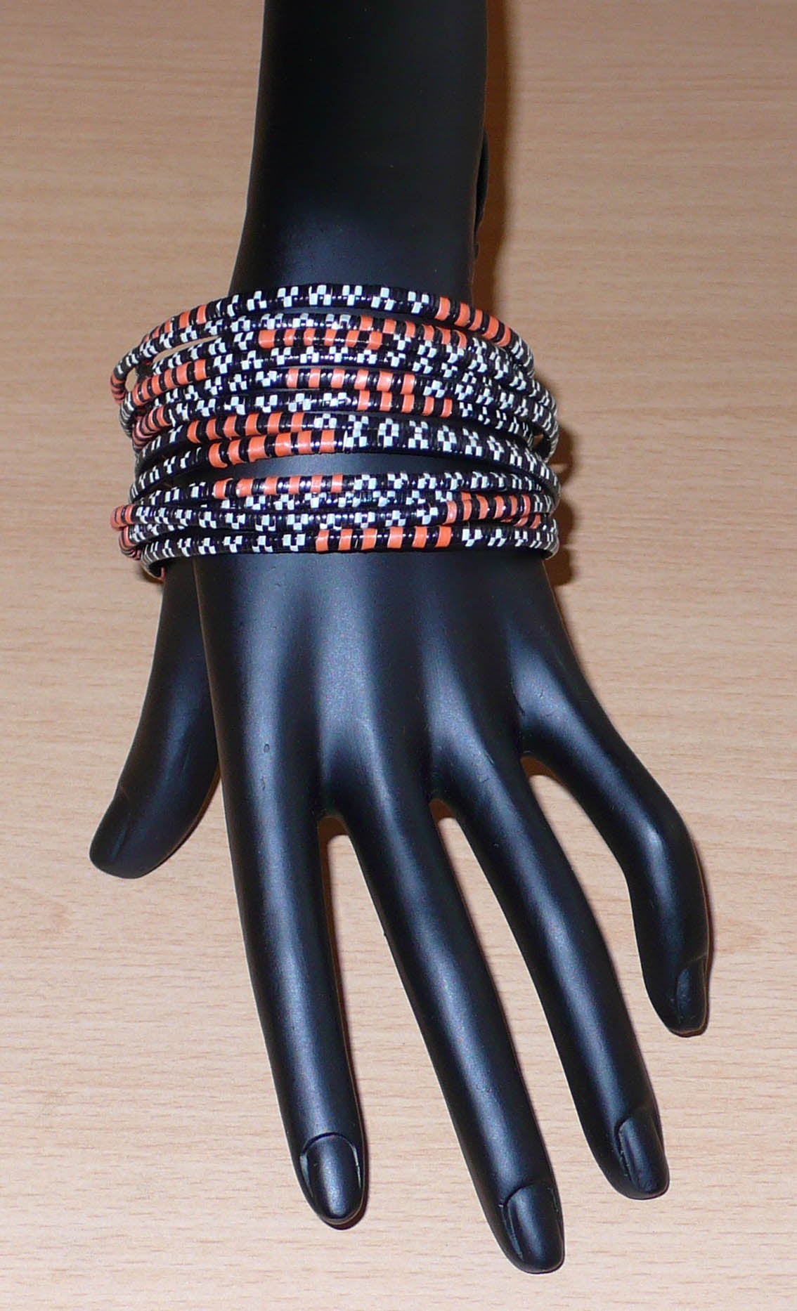 Lot de douze bracelets africains tricolores, fabriqués au Burkina Faso dans une démarche eco-responsable, composés de plastique recyclé orange, noir et blanc.