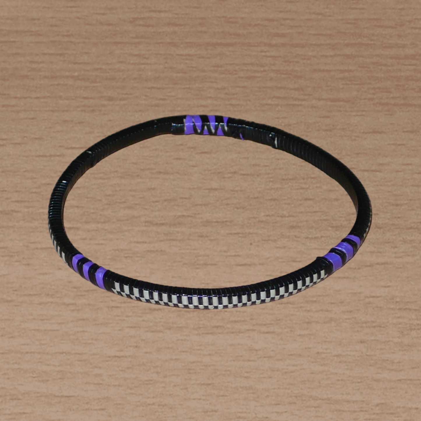 Ensemble de 12 bracelets africains tricolores fabriqués au Mali dans une approche éco-responsable : très fins, ils sont composés de fines bandes de plastique recyclé violet, noir et blanc. Ces bracelets, à empiler sur vos poignets, ont une circonférence de 19.5 cm, un diamètre de 6.3 cm et une épaisseur de 0.4 cm.