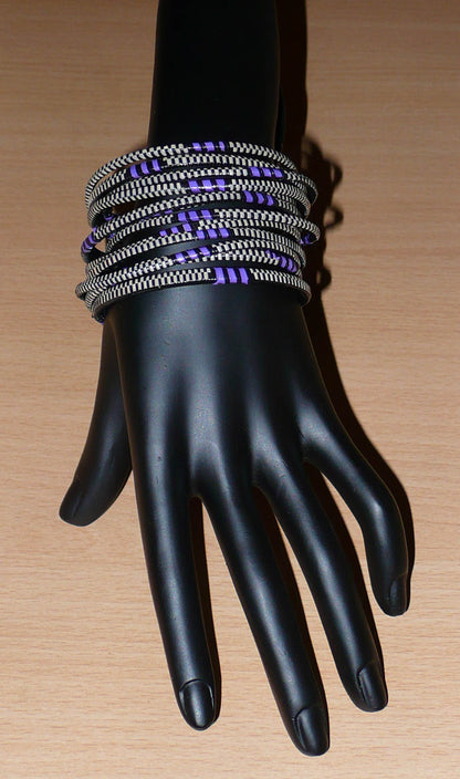 Ensemble de 12 bracelets africains tricolores fabriqués au Mali dans une approche éco-responsable : très fins, ils sont composés de fines bandes de plastique recyclé violet, noir et blanc. Ces bracelets, à empiler sur vos poignets, ont une circonférence de 19.5 cm, un diamètre de 6.3 cm et une épaisseur de 0.4 cm.