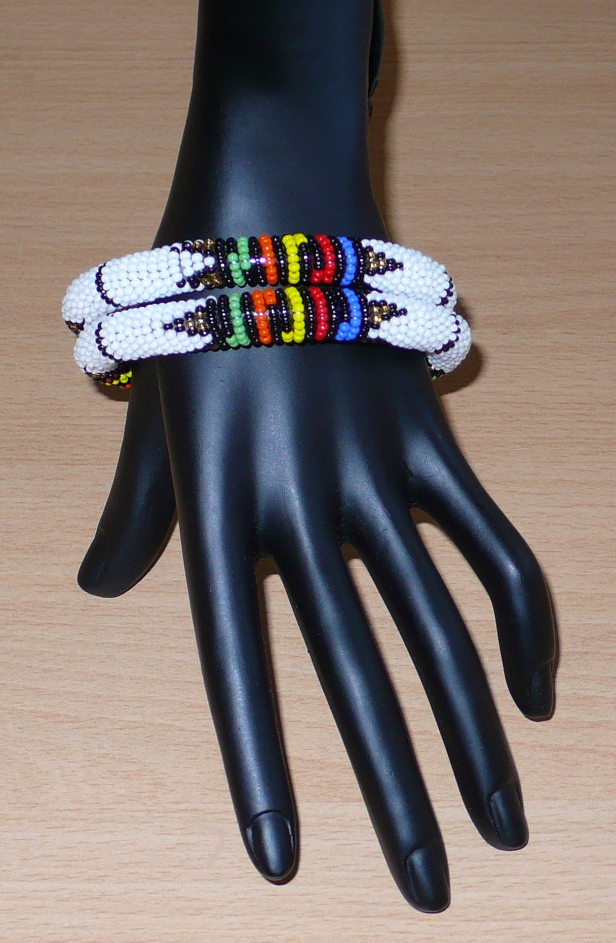 Lot de deux bracelets africains à motifs zoulous traditionnels, composés de perles de rocaille blanches et multicolores.
