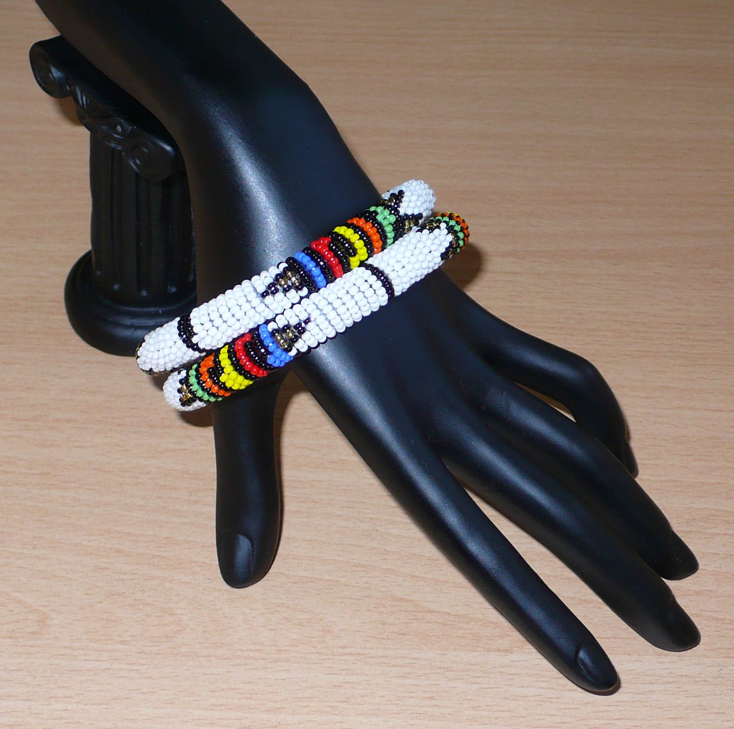 Lot de deux bracelets africains à motifs zoulous traditionnels, composés de perles de rocaille blanches et multicolores.