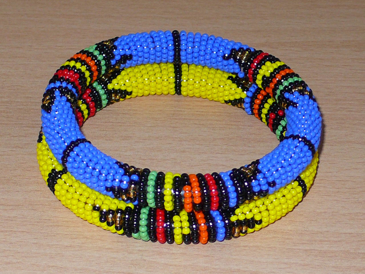 Lot de deux bracelets tubulaires de tradition sud-africaine zouloue, composés de perles de rocaille bleues pour l'un et jaunes pour l'autre, et de perles multicolores pour les motifs.