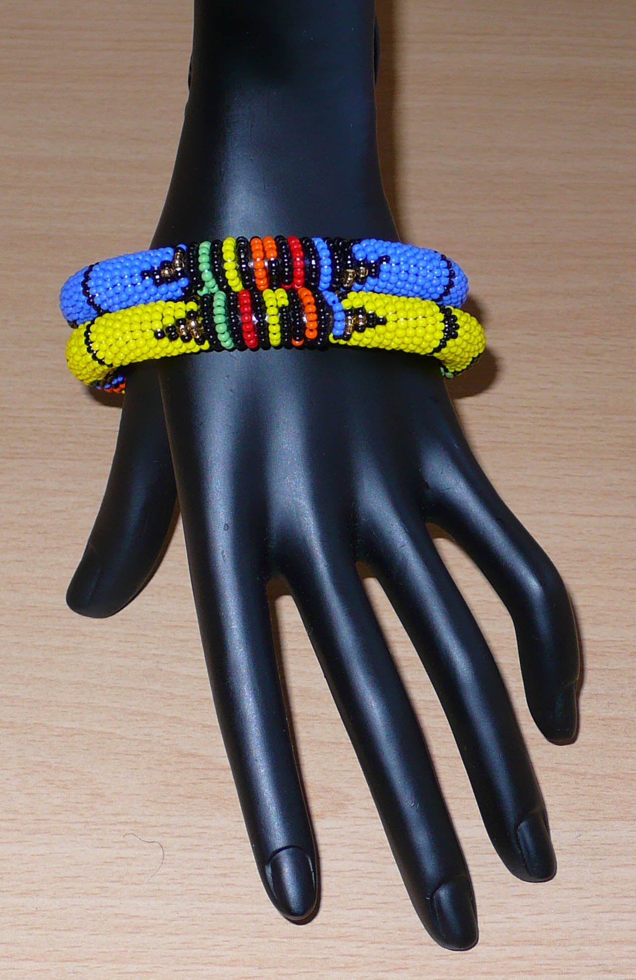 Lot de deux bracelets tubulaires de tradition sud-africaine zouloue, composés de perles de rocaille bleues pour l'un et jaunes pour l'autre, et de perles multicolores pour les motifs.
