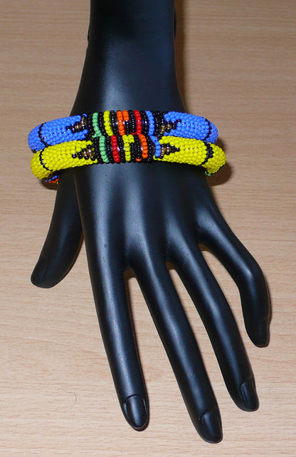 Lot de deux bracelets tubulaires de tradition sud-africaine zouloue, composés de perles de rocaille bleues pour l'un et jaunes pour l'autre, et de perles multicolores pour les motifs.