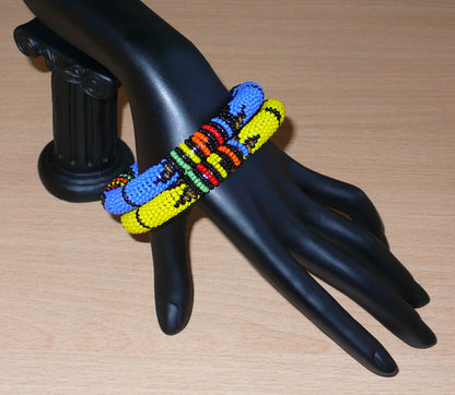 Lot de deux bracelets tubulaires de tradition sud-africaine zouloue, composés de perles de rocaille bleues pour l'un et jaunes pour l'autre, et de perles multicolores pour les motifs.