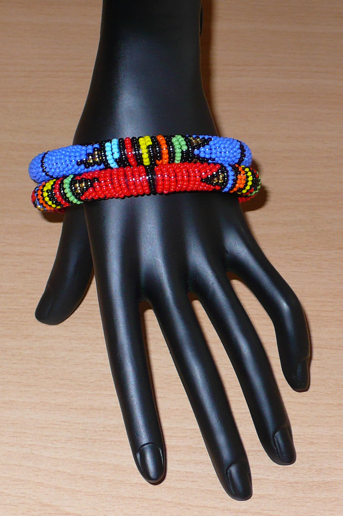 Lot de deux bracelets tubulaires à motifs ethniques de tradition sud-africaine zouloue, composés de perles de rocaille bleues pour l'un et rouges pour l'autre, et de perles multicolores.