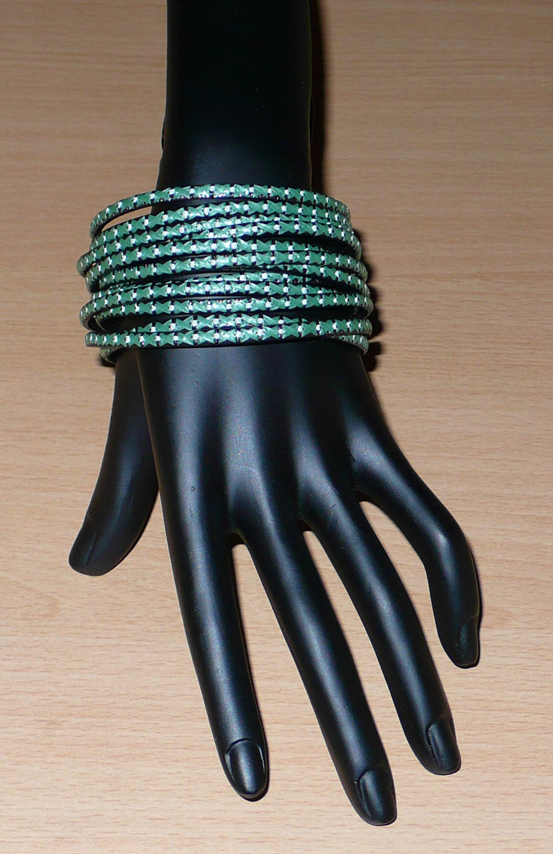 Lot de douze bracelets ethniques fabriqués au Mali dans une perspective eco-responsable, avec de fines bandes de plastique recyclé vert khaki, noir et blanc.