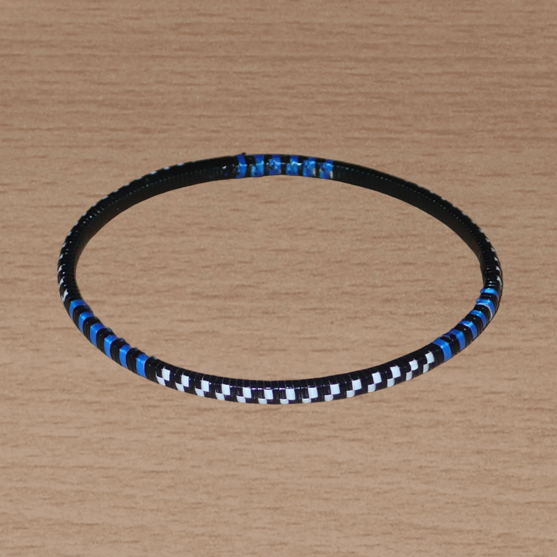 Lot de douze bracelets africains tricolores bleus, blancs et noirs, faits de lamelles en carton recouvertes d'un tissage de fines bandes de plastique recyclé.