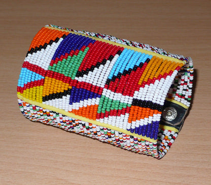 Manchette haute multi-rangs à motifs géométriques ethniques Massai composée de perles de rocaille multicolores ; elle s'attache avec trois boutons pressions.