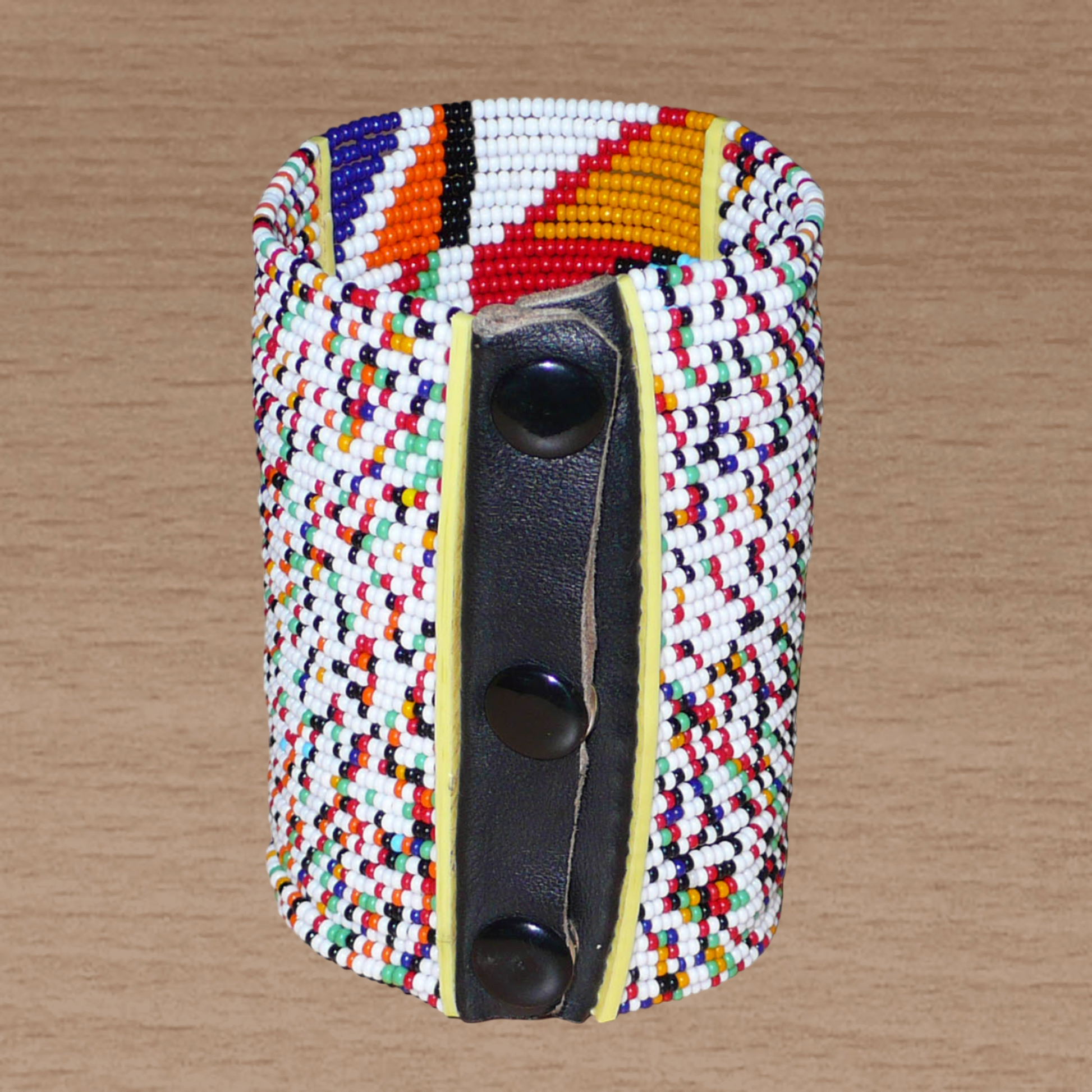 Manchette haute multi-rangs à motifs géométriques ethniques Massai composée de perles de rocaille multicolores ; elle s'attache avec trois boutons pressions.