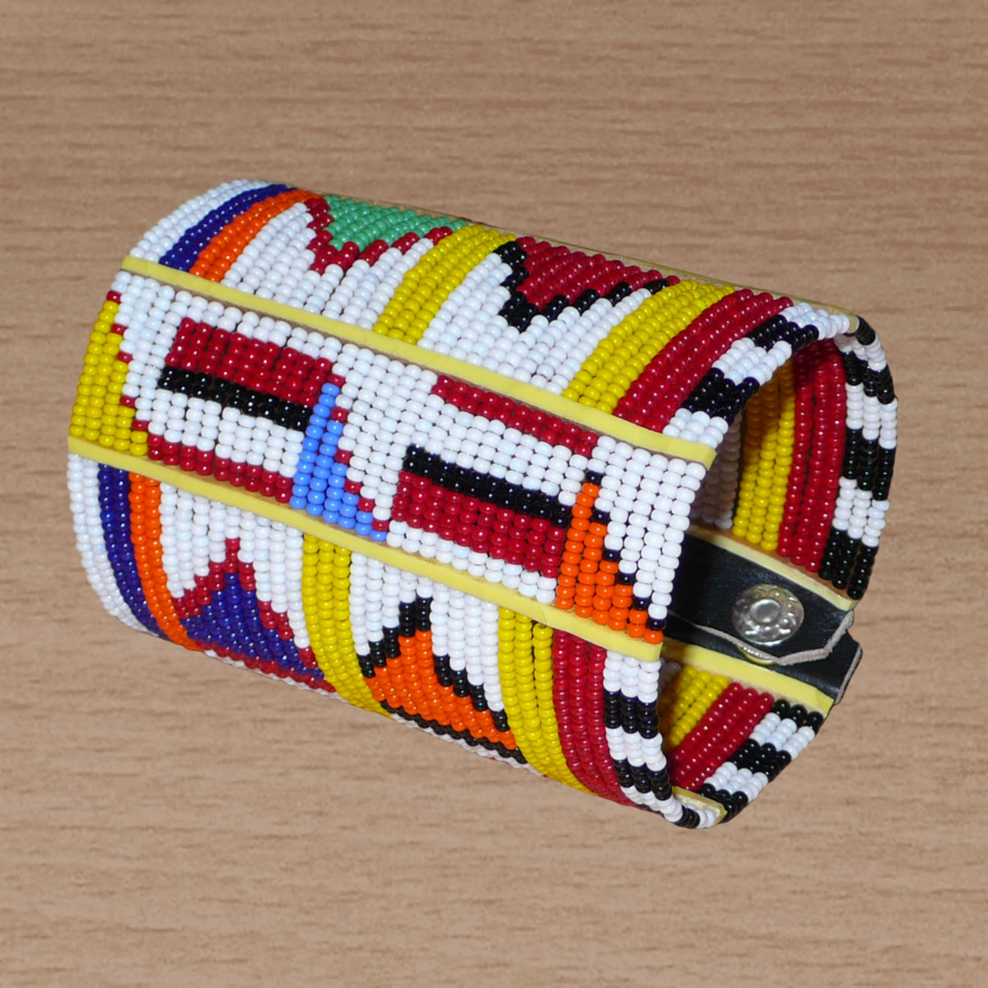Manchette africaine perlée à motifs ethniques Massai composée de plusieurs rangs de perles de rocaille multicolores glissées sur des fils de fer fixés sur des charnières en plastique.