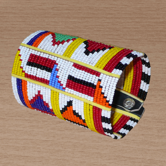 Manchette africaine perlée à motifs ethniques Massai composée de plusieurs rangs de perles de rocaille multicolores glissées sur des fils de fer fixés sur des charnières en plastique.