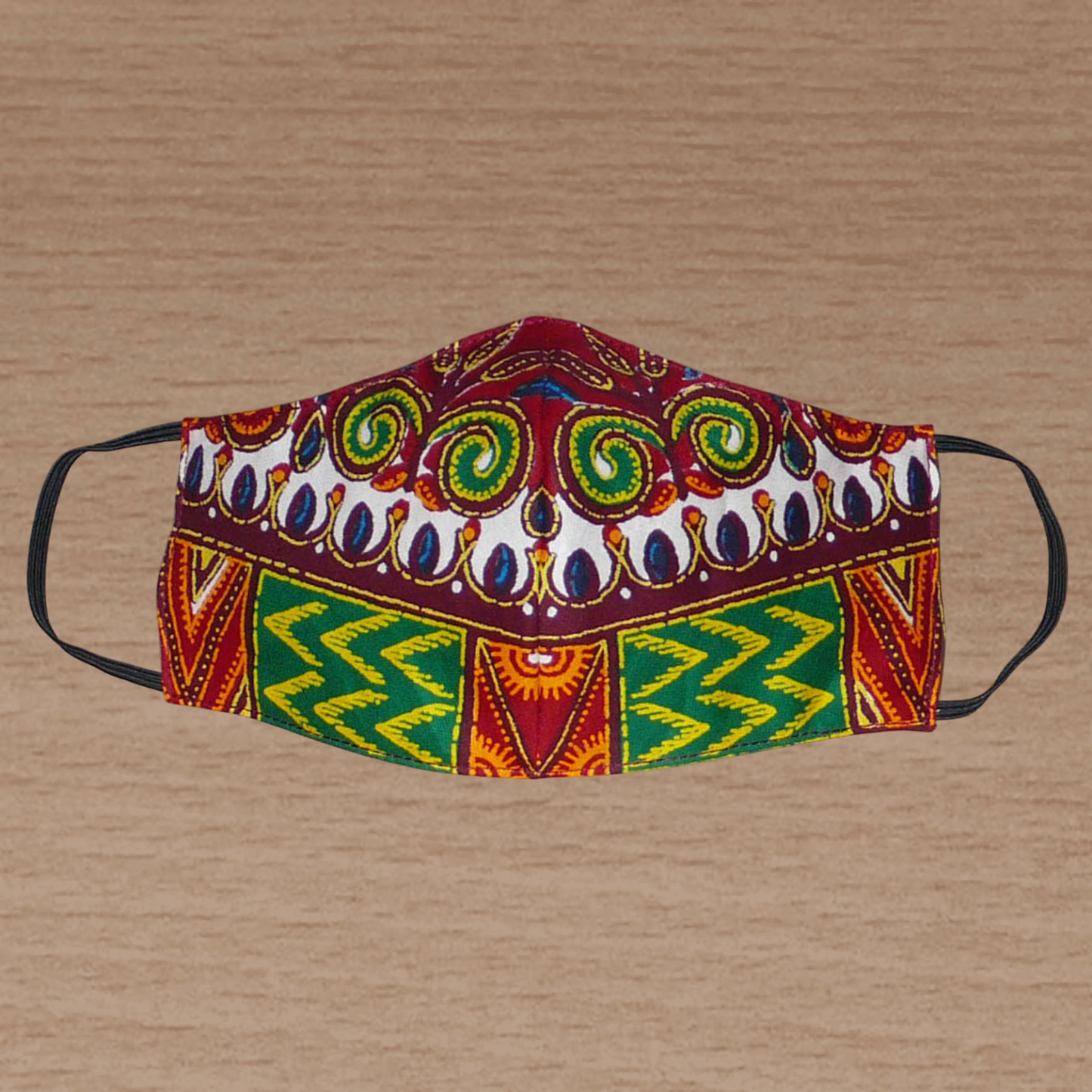 Masque textile ajusté, coupé et cousu dans un tissu africain en coton imprimé de motifs ethniques et floraux multicolores ; il se porte avec des élastiques. Fabriqué dans une démarche éco-responsable, ce masque est lavable et réutilisable.
